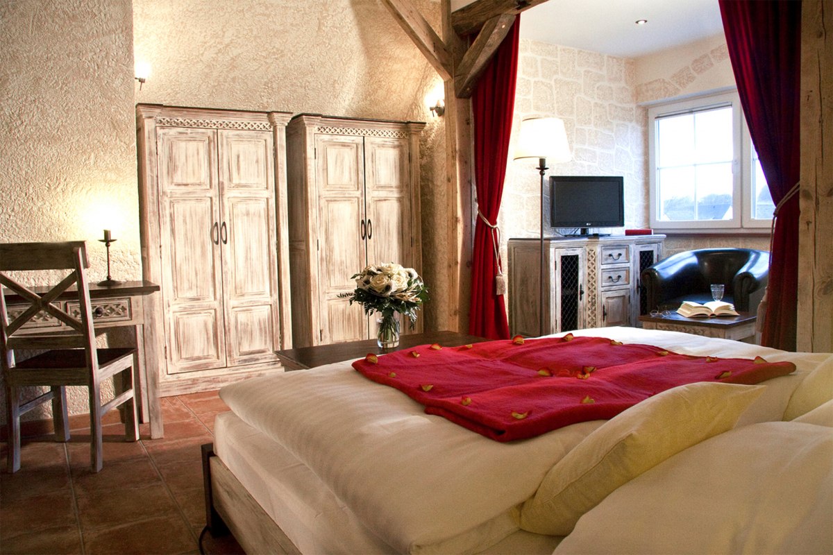 &ldquo;Kastell GiebelStube  Romantik-Traum&rdquo;(DZ f&uuml;r max. 2 Personen, keine Kinder)Romantik Stil:Holzbalkenbett oder gotisches Metallbett. Erker mit Sesseln/Sofa.32? / 81cm LED-TV mit Radio. Schreibtisch.Du & WC. Kosmetikspiegel & Haartrockner.ca. 25  m&sup2; im Dachgeschoss im Haus Kastell. // &copy; BinzHotel.de/Eigent&uuml;mer/WAECHTER