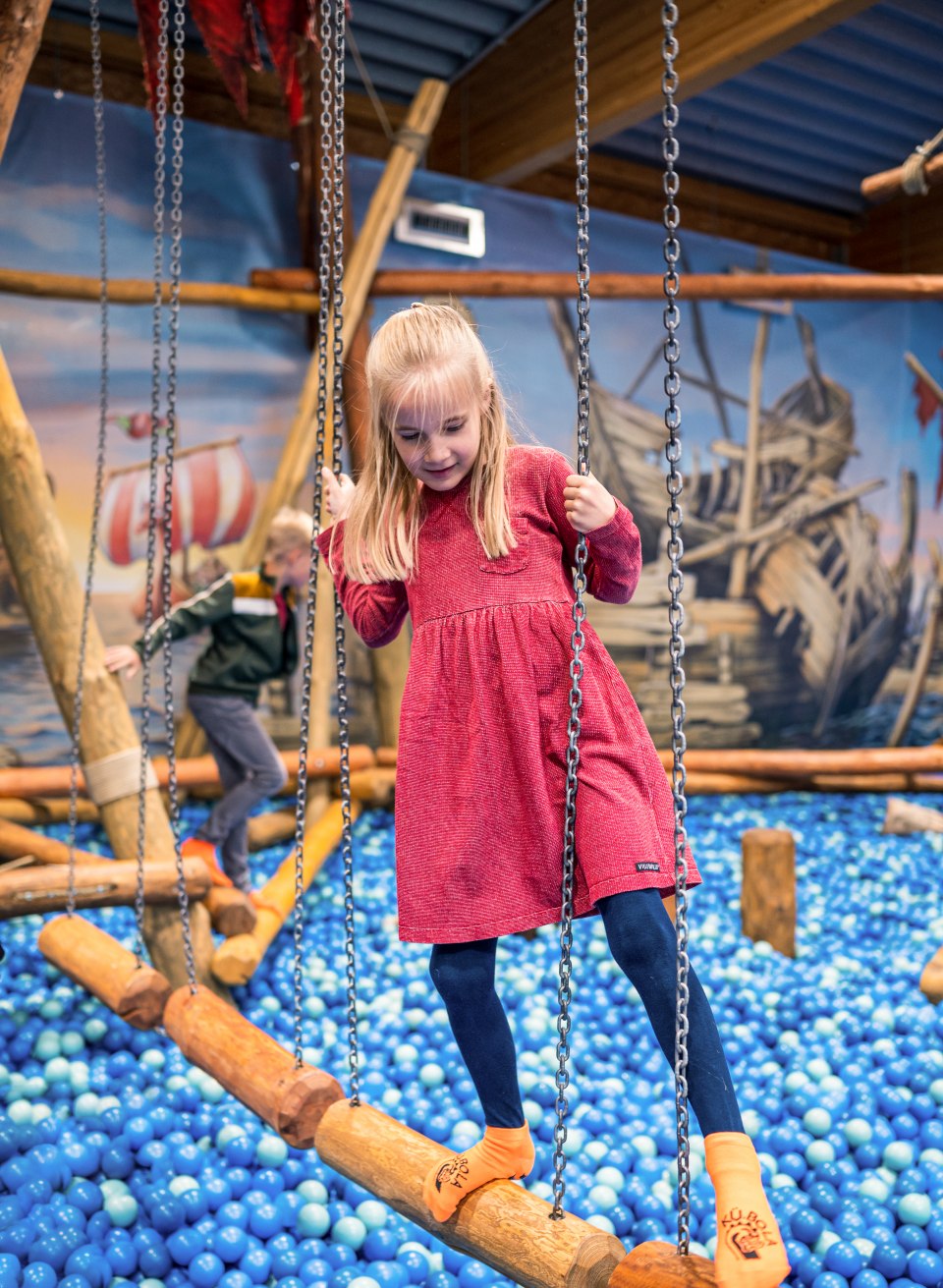 Ein Kind balanciert im Indoorspielplatz über ein Bällebad. // Balanceakt über wackeligem Grund: Spielnachmittag im KüBoLa in Kühlungsborn // © MV-T/Tiemann Ein Kind balanciert im Indoorspielplatz über ein Bällebad.
