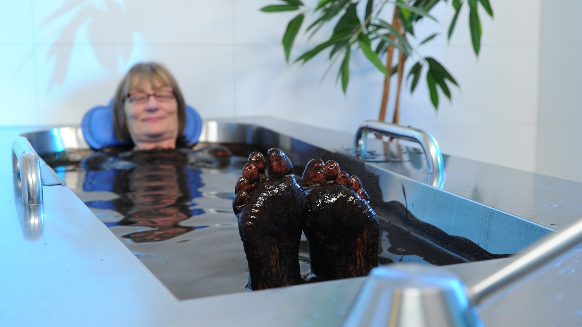 Naturmoorbad in einer speziellen Wanne - eine Frau badet darin entspannt.
