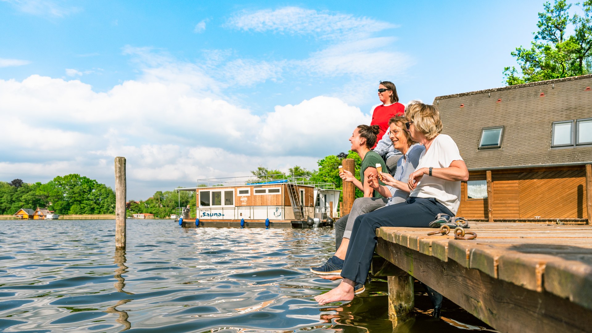 Auf dem Steg vor Schloss Mirow lässt es sich gut schnacken. Das Hausboot im Hintergrund ruht sich so lange ein bisschen aus., © TMV/Tiemann Auf dem Steg vor Schloss Mirow lässt es sich gut schnacken. Das Hausboot im Hintergrund ruht sich so lange ein bisschen aus., © TMV/Tiemann