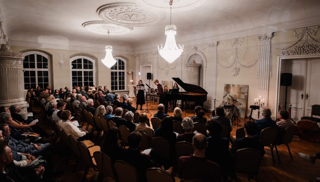 Toeschouwers beleven een klassiek concert in de feestelijk verlichte zaal van kasteel Vietgest tijdens het Schl&ouml;sserherbst festival.