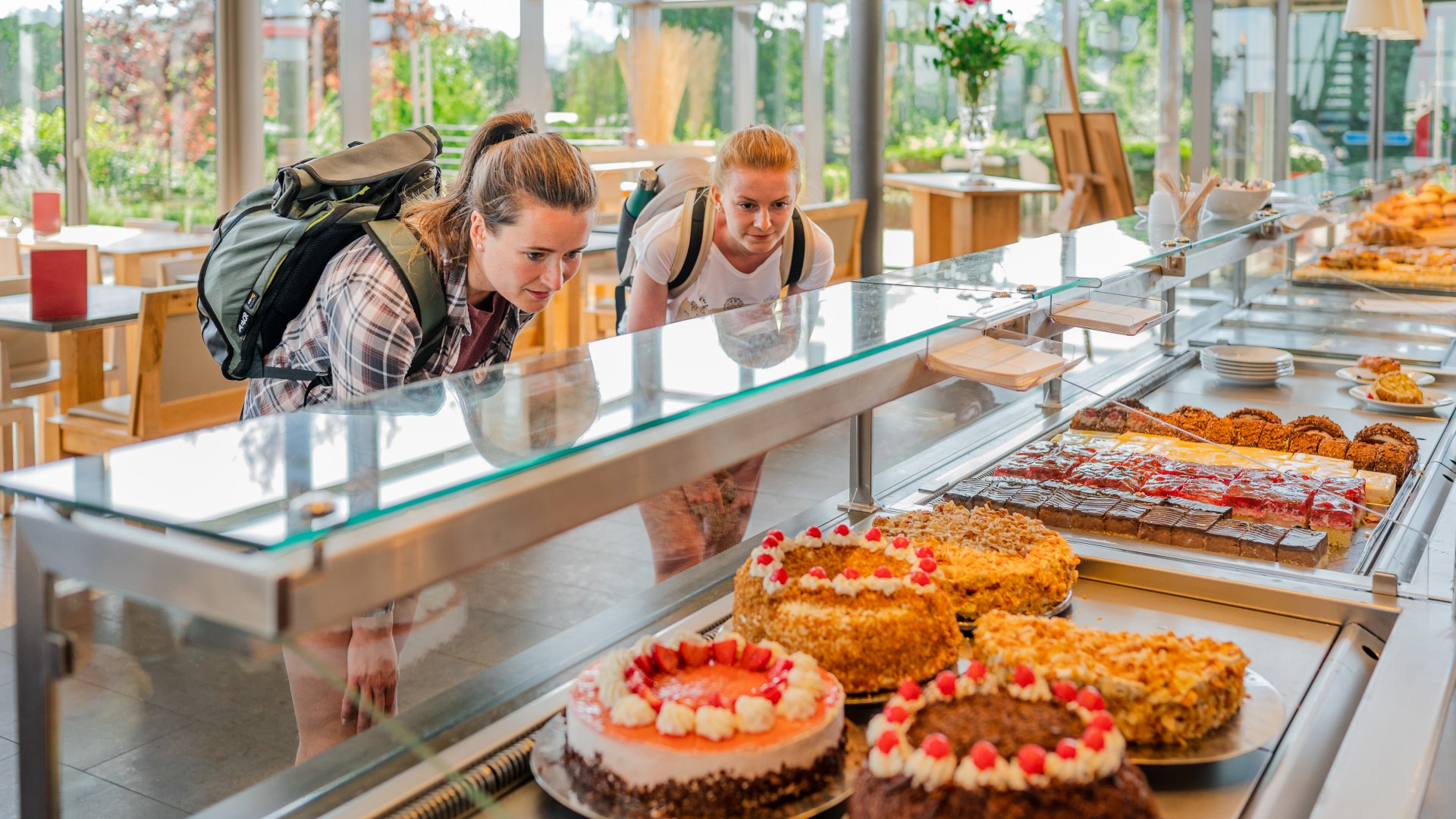 Zwei Frauen schauen durch die Vitrine auf ein Kuchenbuffet beim B&auml;cker