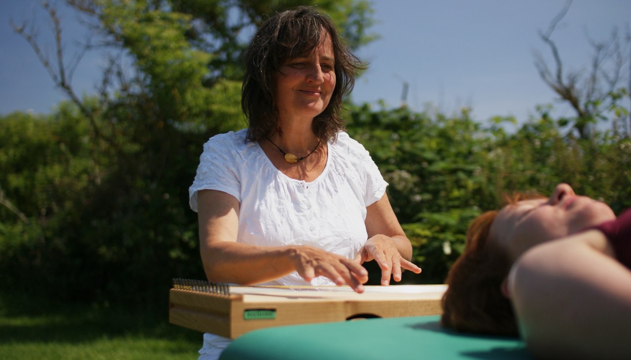 Martina Gl&auml;ser-B&ouml;hme spielend am Monochord - auf der Liege eine Klientin, &copy; Martina Gl&auml;ser-B&ouml;hme