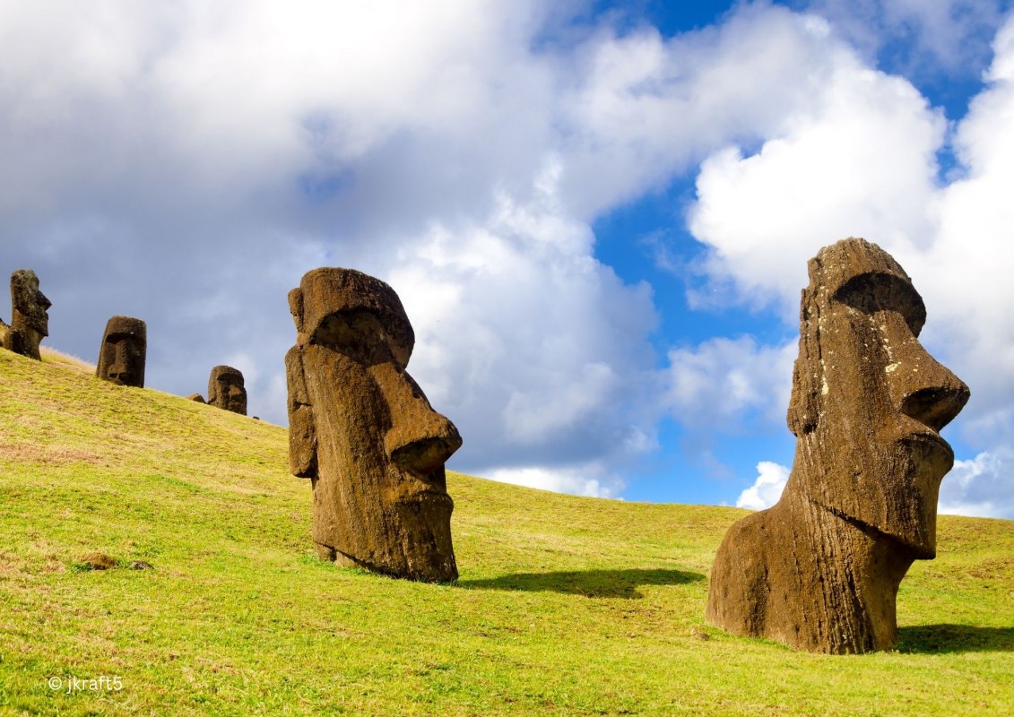 Steingesichter an einem gr&uuml;nen Hang, im Hintergrund der Himmel mit Wolken, &copy; Umweltprojekte Nord e.V.