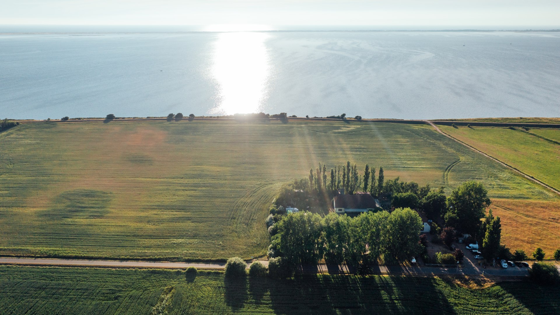 Das Ummaii Surfhostel aus der Luft mit Blick auf die Ostsee beim Sonnenuntergang