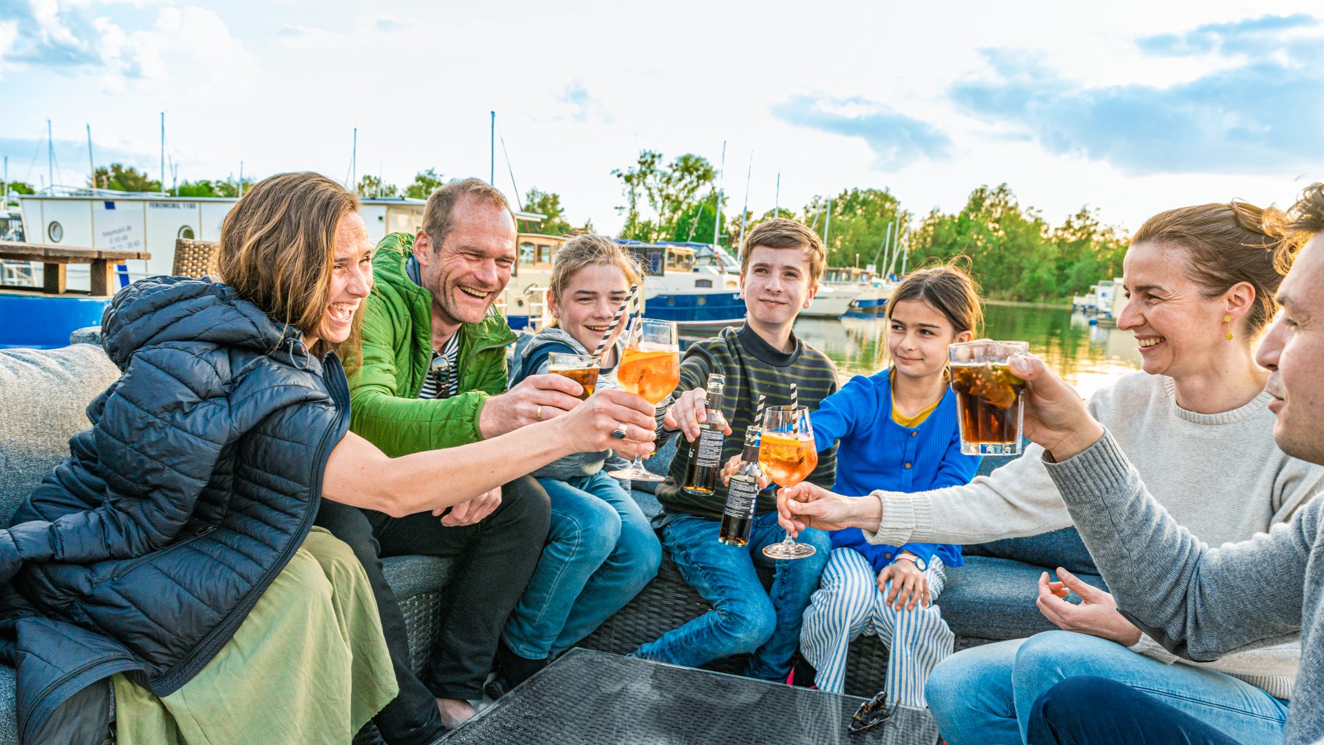 Zwei Familien stoßen mit Getränken an in der Pirate`s Bar. // Schöner Ausklang in der Pirate’s Bar: Mit den Füßen im Sand stoßen die beiden befreundeten Familien auf den tollen Urlaub an. // © MV-T/Tiemann Zwei Familien stoßen mit Getränken an in der Pirate`s Bar.