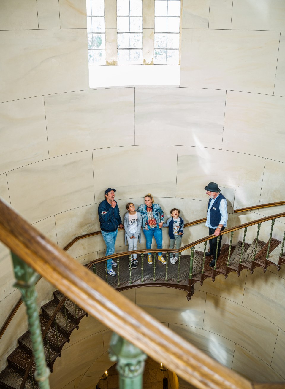 "Traut ihr euch ganz hinauf?" Die Treppe im Mittelturm erfordert Schwindelfreiheit., © TMV/Tiemann Eine Familie steht auf der Wendeltreppe im Schloss Granitz die in den Turm geht.