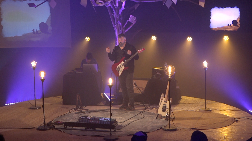Alain erzählt und spielt Gitarre. // © Atelier Auderset Alain erzählt und spielt Gitarre. // © Atelier Auderset
