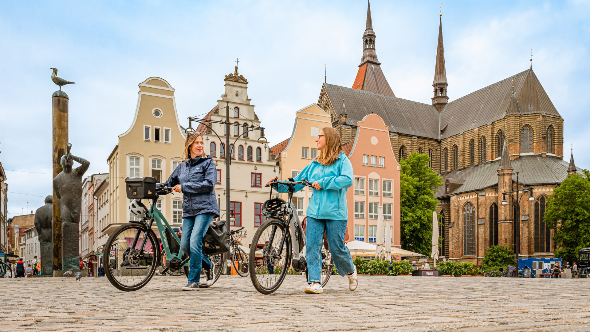 Mutter und Tochter schiebn ihre Fahrräder über den Rostocker Marktplatz
