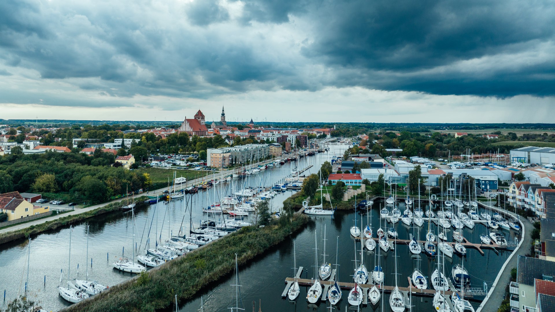 Schiffsmasten im Hafen von Greifswald mit sch&ouml;nster Wolkendramatik. Die Stadt im Hintergrund als Silhouette.