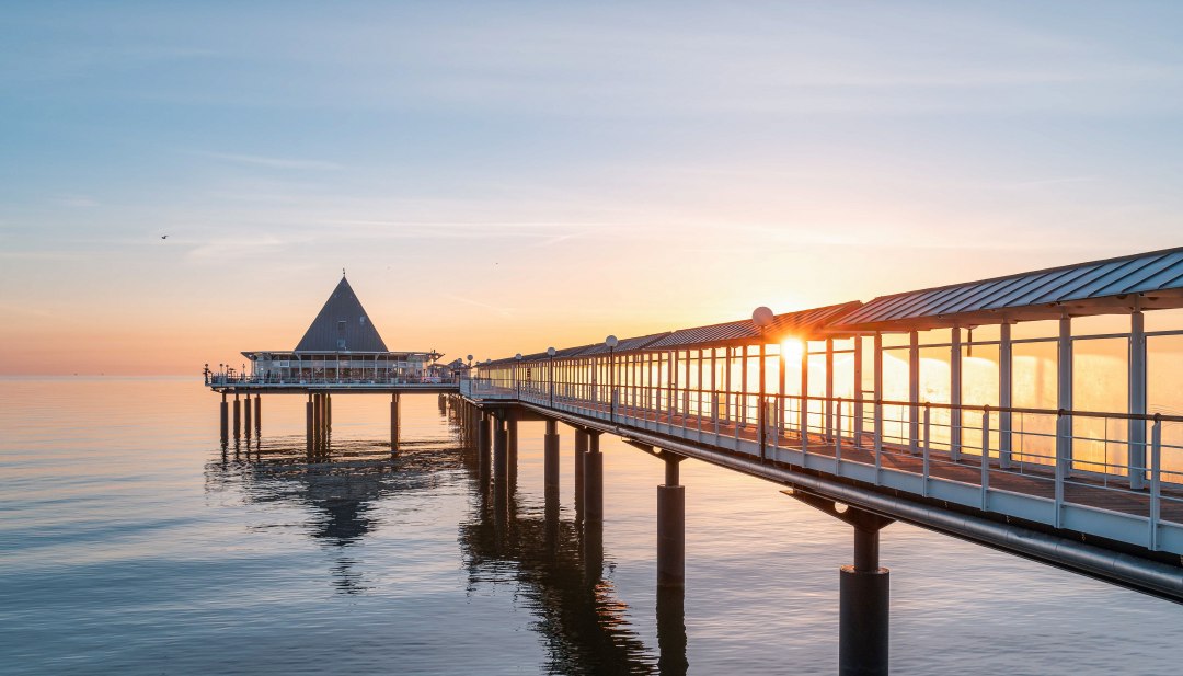 Seebrücke Heringsdorf auf Usedom im goldenen Licht des Sonnenaufgangs über der ruhigen Ostsee.