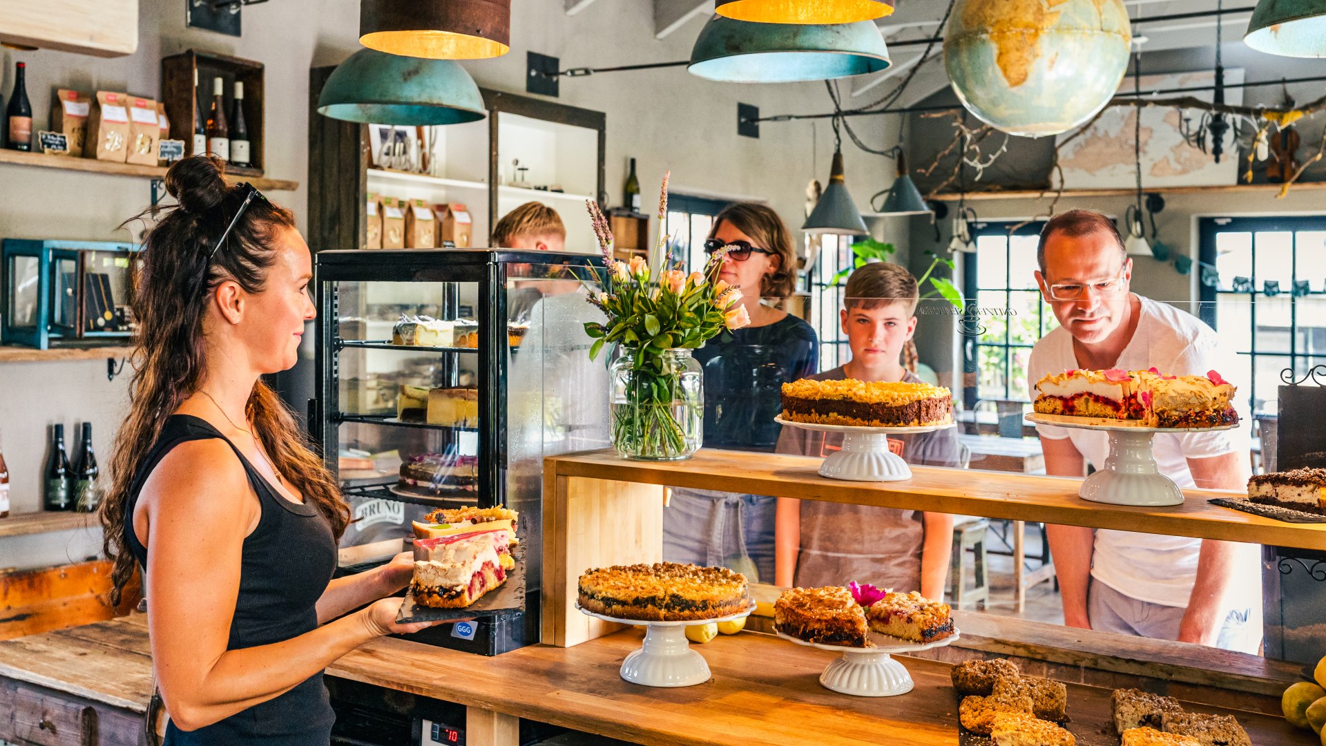 Café Gnitzer Seelchen – en familie står ved disken med et kagebord. // Også caféen »Gnitzer Seelchen« er et af familiens yndlingssteder. Intet sted smager kagerne bedre. // © MV-T/Tiemann Café Gnitzer Seelchen – en familie står ved disken med et kagebord.