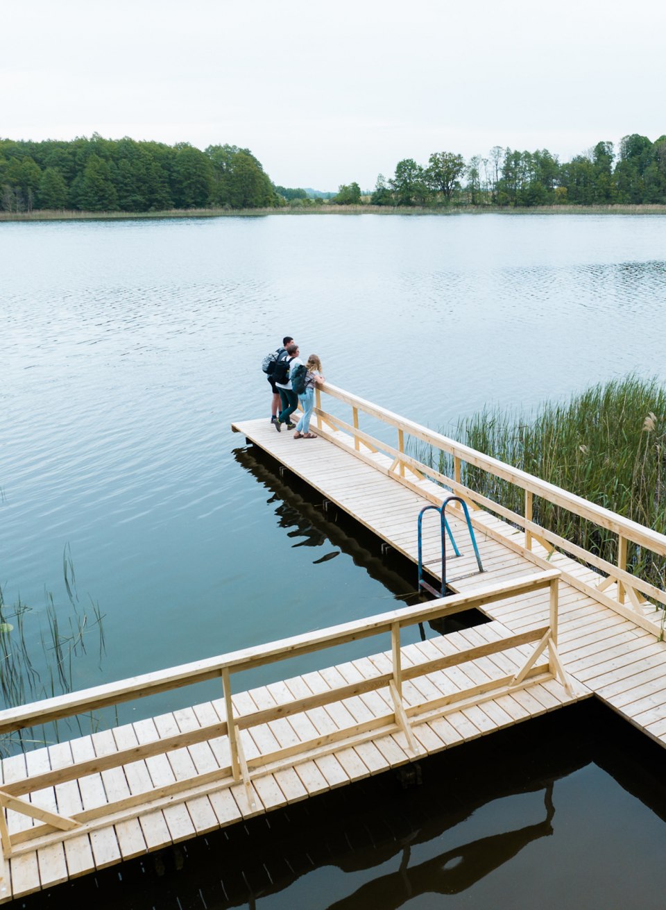 Drei Freunde stehen auf dem Steg am Gro&szlig; Radener See und schauen aufs Wasser