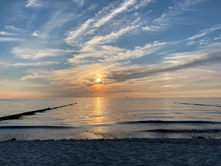 Das Bild zeigt die spiegelglatte Ostsee, dessen ruhige Wasseroberfläche die Farben des Sonnenuntergangs widerspiegelt. Der Himmel ist teilweise hellblau, durchzogen von feinen Schlierenwolken, die dem Panorama eine sanfte Dynamik verleihen. Am Rand des Motivs erstreckt sich ein friedlicher Strand, der zum Verweilen einlädt. Die Atmosphäre wirkt ruhig und harmonisch, als würde die Welt für einen Moment innehalten, um die Schönheit des Augenblicks zu genießen., © byc Das Bild zeigt die spiegelglatte Ostsee, dessen ruhige Wasseroberfläche die Farben des Sonnenuntergangs widerspiegelt. Der Himmel ist teilweise hellblau, durchzogen von feinen Schlierenwolken, die dem Panorama eine sanfte Dynamik verleihen. Am Rand des Motivs erstreckt sich ein friedlicher Strand, der zum Verweilen einlädt. Die Atmosphäre wirkt ruhig und harmonisch, als würde die Welt für einen Moment innehalten, um die Schönheit des Augenblicks zu genießen., © byc