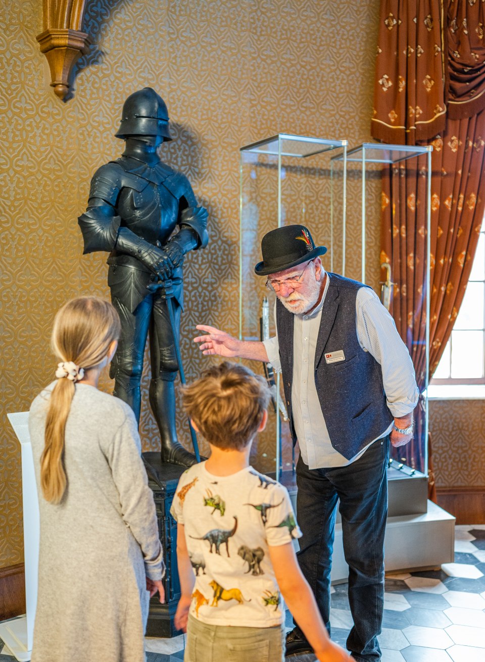 Schlossführer erklärt den Kindern die Schlossgeheimnisse und die Geschichte zu einer Ritterrüstung // Sieht aus wie eine Rüstung, ist aber ein Ofen: Herr Stohmann erklärt die Schlossgeheimnisse. // © MV-T/Tiemann Schlossführer erklärt den Kindern die Schlossgeheimnisse und die Geschichte zu einer Ritterrüstung