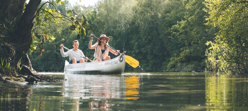 Ein Kanu paddelt am Jamelsee im Sonnenschein