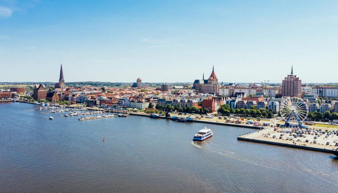 Von oben wirkt der Rostocker Stadthafen wie ein Miniaturwunderland. Selbst das Riesenrad wirkt auf einmal gar nicht mehr so riesig. Gemächlich fährt das Ausflugsschiff an seinen Anlegesteg, um wieder neue Fahrgäste aufzunehmen. , © TMV/Gänsicke