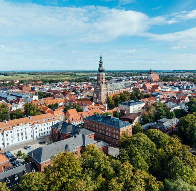 Die Silhouette von Greifswald aus der Luft und Blick auf die Kircht&uuml;rme, sowie Altstadt am Tage.