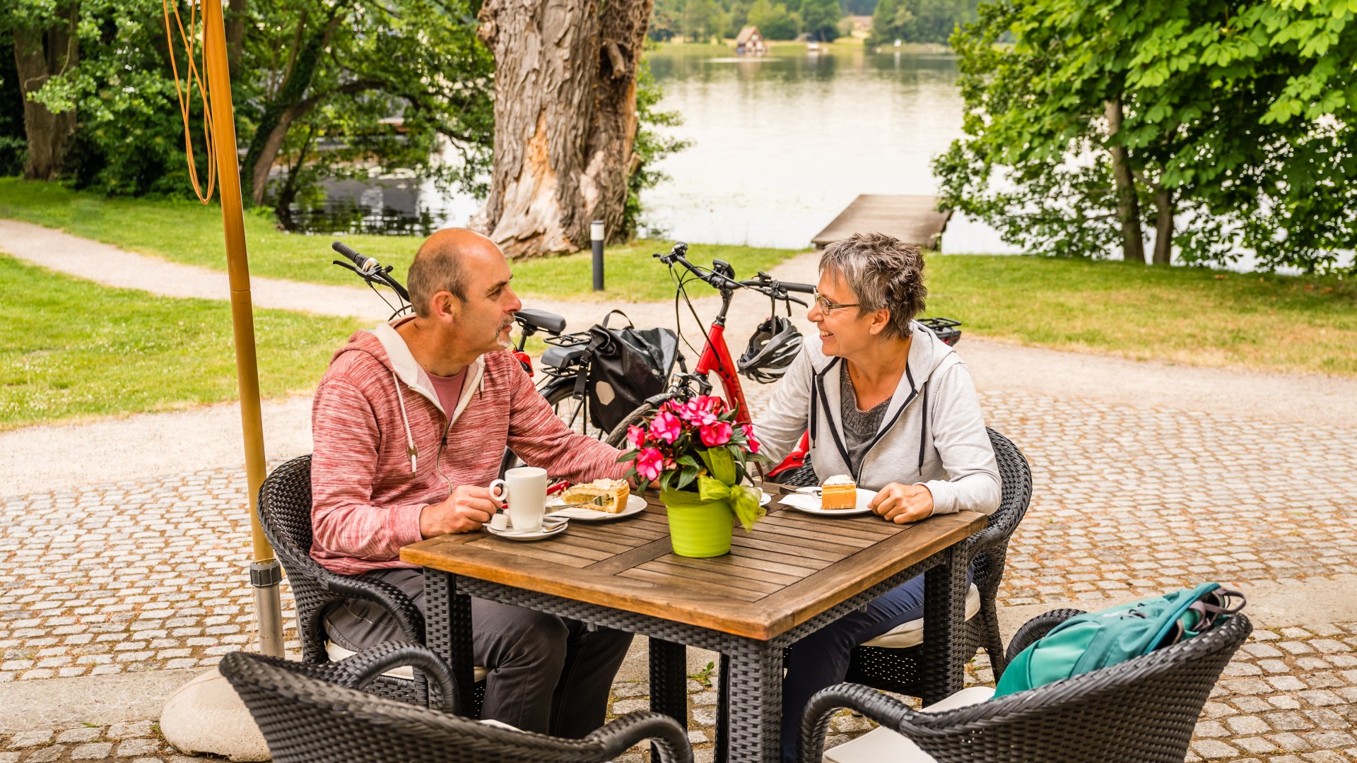 Ein Paar zum Kaffee und Kuchen vor dem Schloss Mirow und dem See im Hintergund